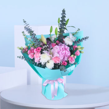 Pink and white flower bouquet wrapped in aqua blue paper with lush green fillers.