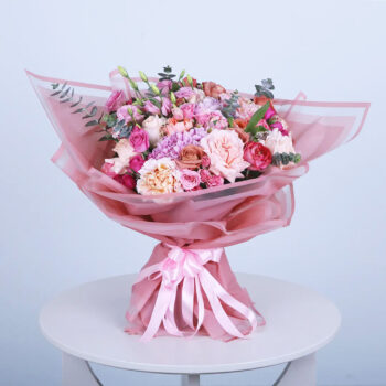 Beautiful hand-tied pink bouquet featuring roses, carnations, and fresh greens.