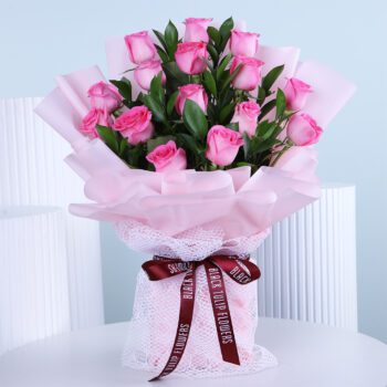 A bouquet of fresh light pink roses wrapped in soft pink paper with a delicate ribbon.