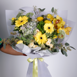 The bouquet features prominent yellow Gerbera daisies with dark centers