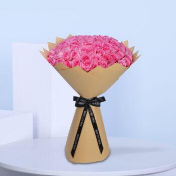 A bouquet of pink roses arranged in a rustic brown paper bag.