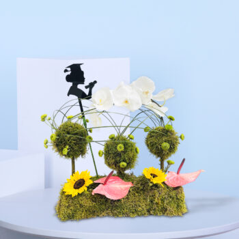 Graduation-themed flower arrangement with orchids, sunflowers, moss balls, anthuriums, and a graduate silhouette decoration.