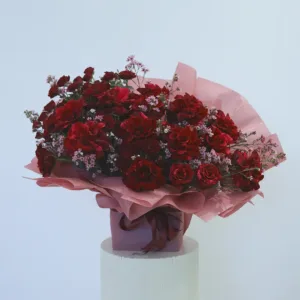 A bouquet of rich red roses, elegantly wrapped in soft pink, perfect for expressing love and passion.