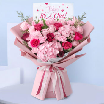 Pink baby girl bouquet with roses, hydrangeas, carnations, and “It’s a Girl” card.