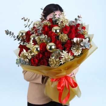 Christmas bouquet with red roses, gold pinecones, golden ornaments, and with festive wrapping