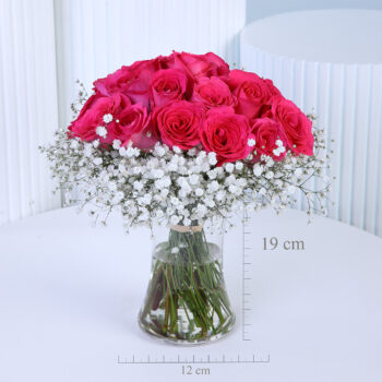 20 pink roses with baby’s breath in a clear glass vase.
