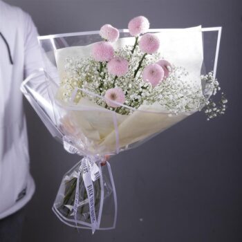 Bouquet featuring hand-tied purple ping pong and baby’s breath in a clear wrap, finished with branded ribbon.