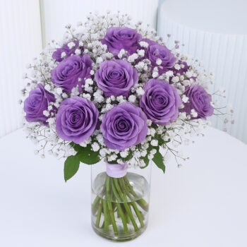 20 purple roses and baby’s breath in a clear glass vase arrangement, with a blank message card.