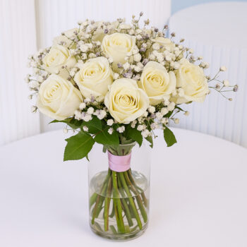 20 white roses with baby’s breath in a clear glass vase.