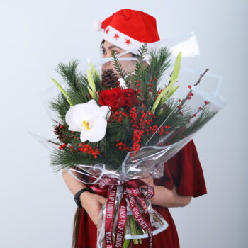 Christmas bouquet with orchid, red roses, winter pine, berries, and festive ribbon wrappin